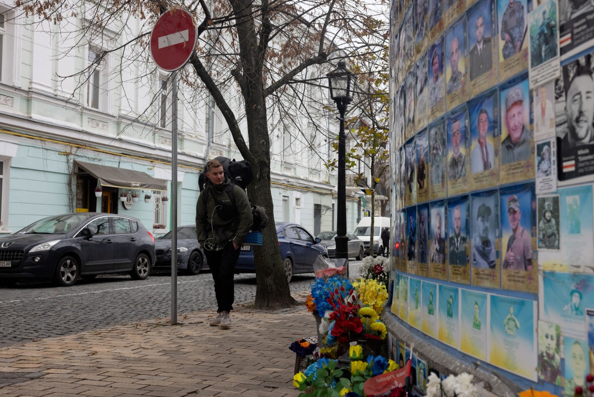 رجل يسير بجوار جدار إحياء ذكرى شهداء أوكرانيا (أ ف ب)