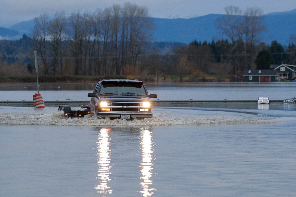 سائق يعبر مياه الفيضانات في مدينة سنوهوميش بولاية ‏واشنطن (أ ف ب)‏