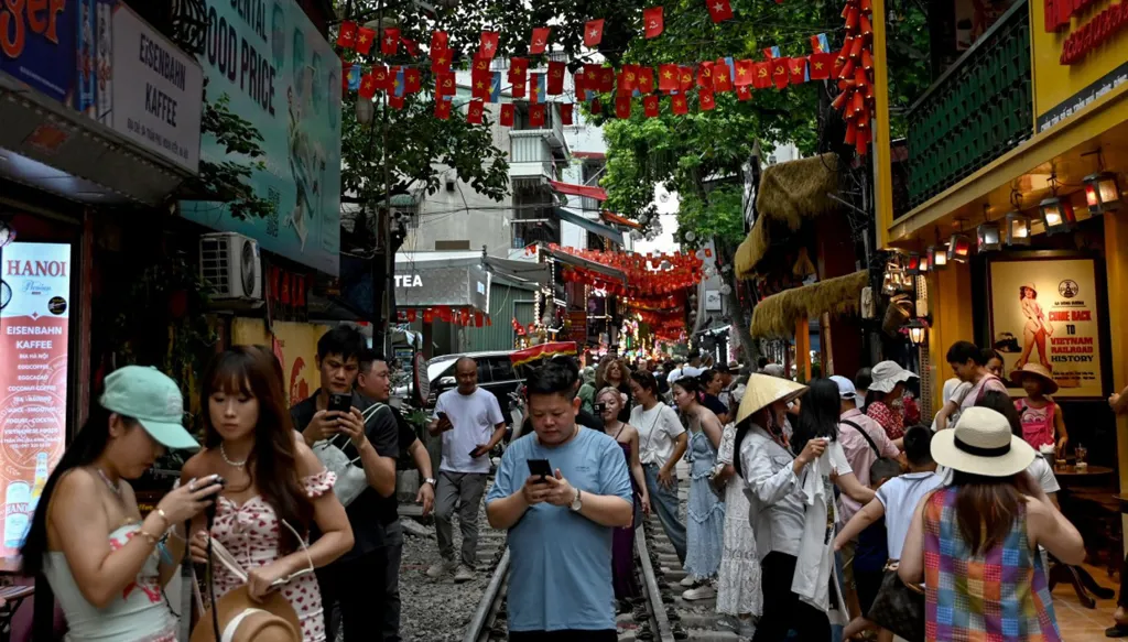 سواح يسيرون على طول خط سكة حديد بين المقاهي وسط هانوي (أ ‏ف ب)‏