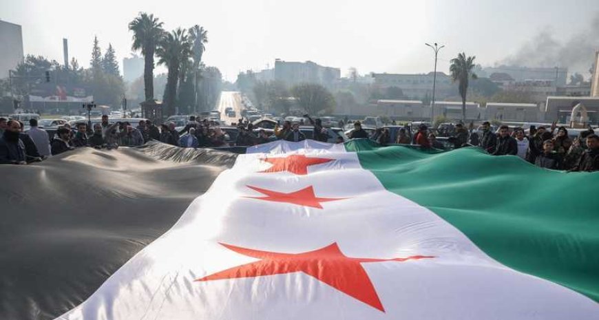 رفع علم سوريا الجديد خلال الاحتفالات بسقوط الأسد ( أ ف ب)‏
