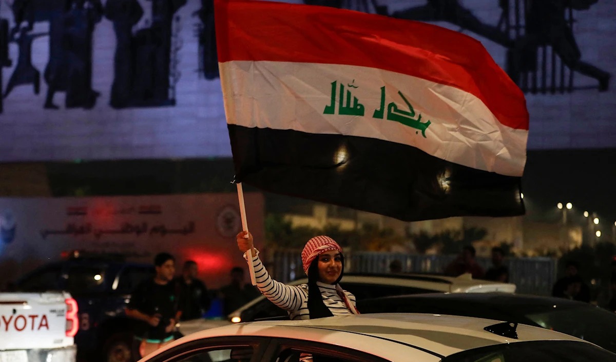 امرأة تلوّح بالعلم العراقي خلال احتفال لأنصار السوداني عقب إعلان النتائج الأولية للانتخابات النيابية في بغداد. (أ ف ب)