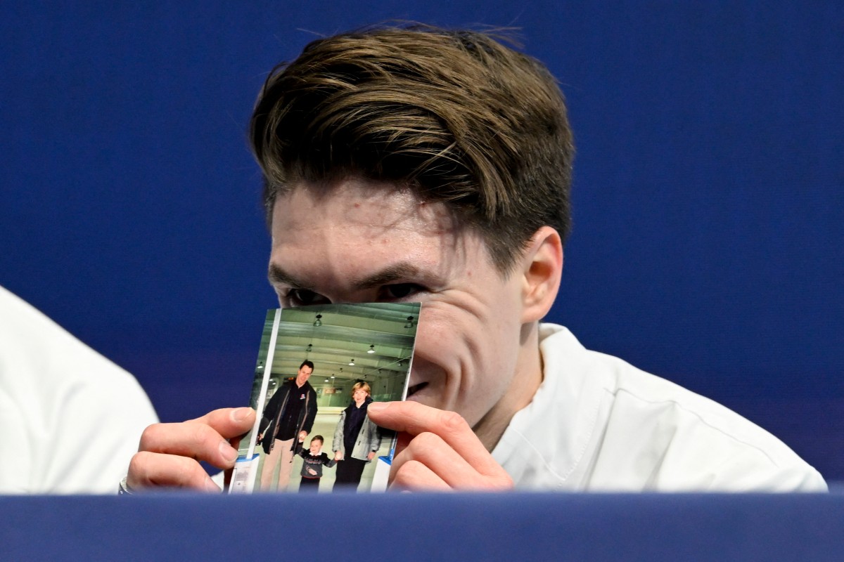 مكسيم ناوموف حاملاً صورة والديه الراحلين. (أ ف ب)