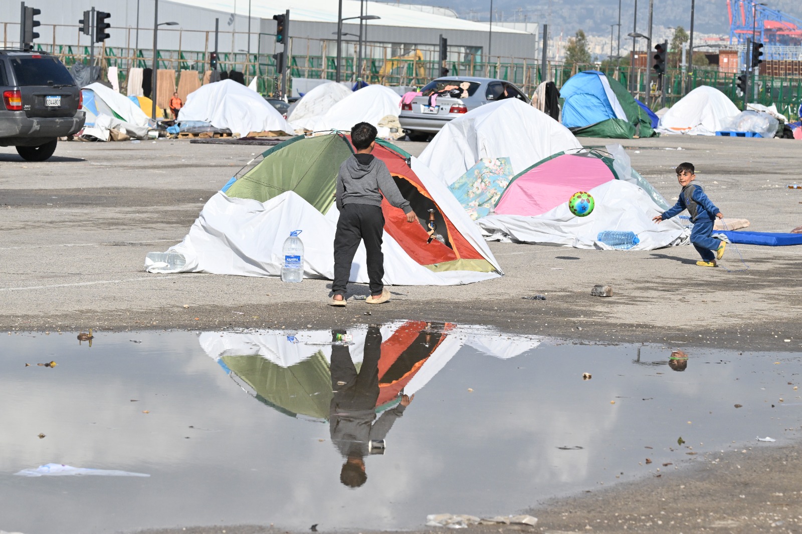 قرب البيال، ظل طفل نازح في تجمع مياه الأمطار