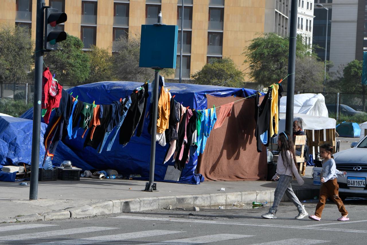 طفلتان تسيران معاً قرب الخيام