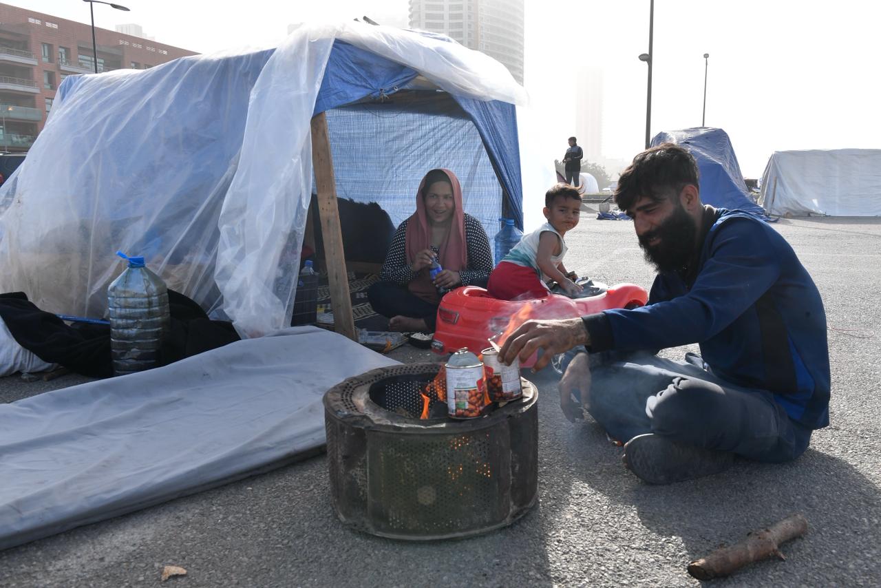 رجل يعد الطعام قرب خيمة نزوح عائلته في واجهة بيروت البحرية.