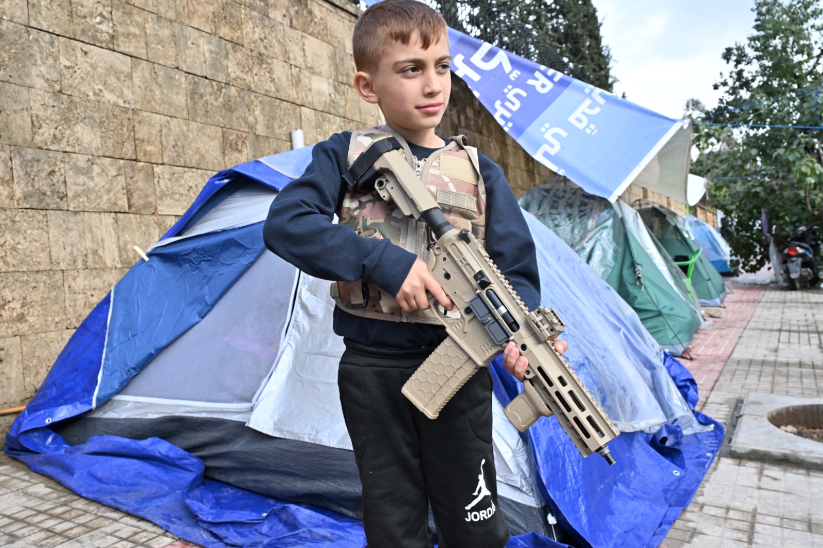 طفل يلهو بلعبة سلاح في مجمع خيم في حرش بيروت.