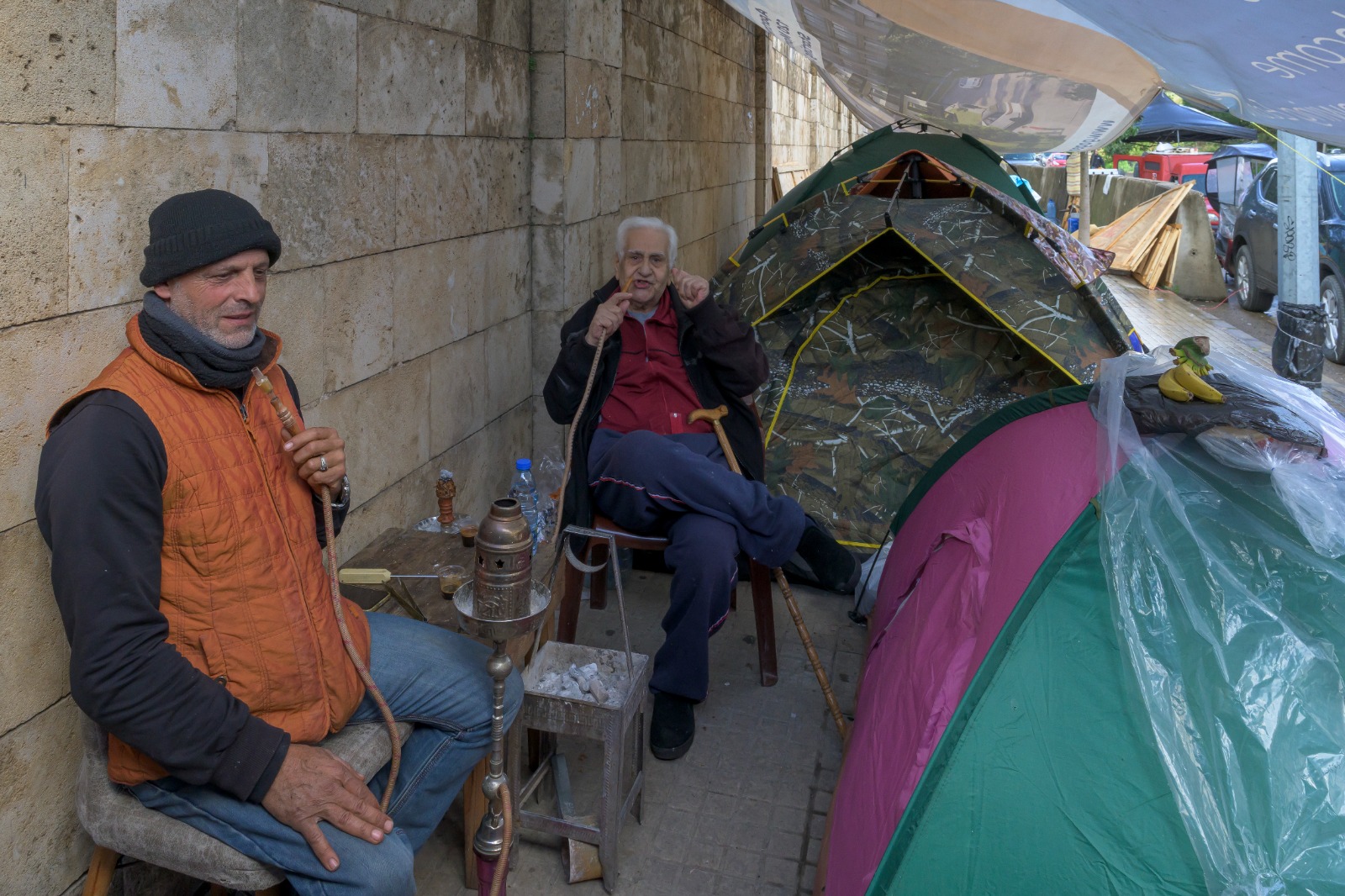 نازحان يدخنان الأرجيلة في مجمع لخيم النزوح في حرش بيروت