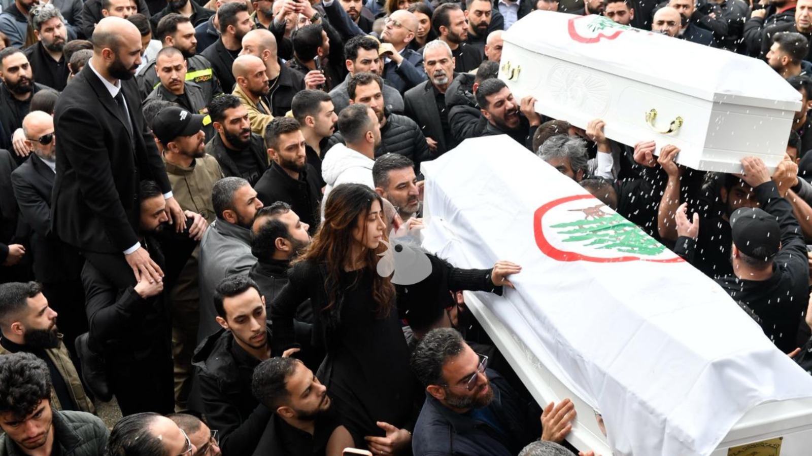 نُثر الأرز على الكفنين أثناء المراسم الوداعية، وفي الصورة تبدو ابنة الفقيدين تضع يدها على نعش أحد والديها