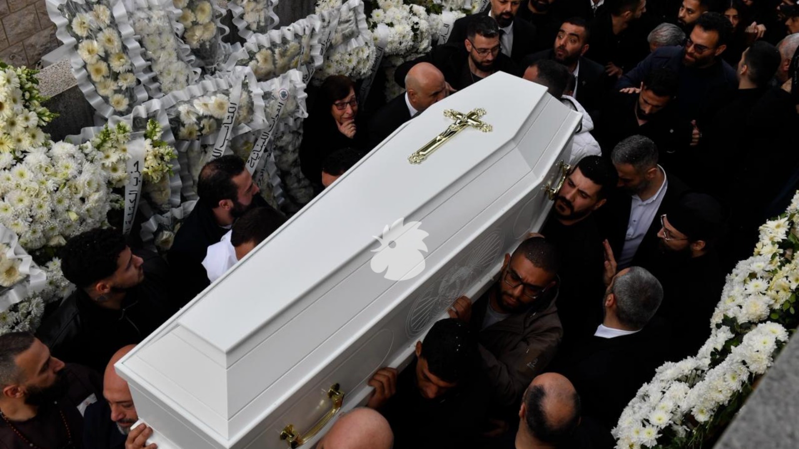 كفنا بيار معوّض وزوجته على الأكُف وتبدو الأكاليل الجنائزية في الخلف