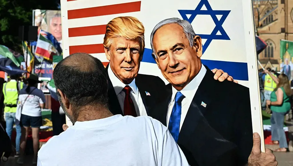 A person from the Iranian community in Australia holds a sign supporting U.S. President Donald Trump and Israeli Prime Minister Benjamin Netanyahu. (AFP)