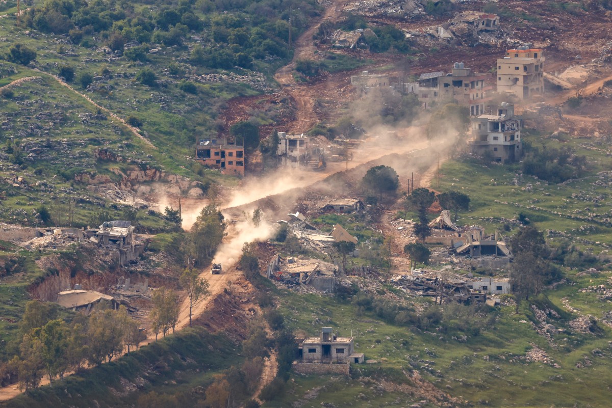 مركبات عسكرية إسرائيلية تسير على طول الطريق بين المنازل المدمرة في جنوب لبنان بالقرب من الحدود مع إسرائيل. (أ ف ب)