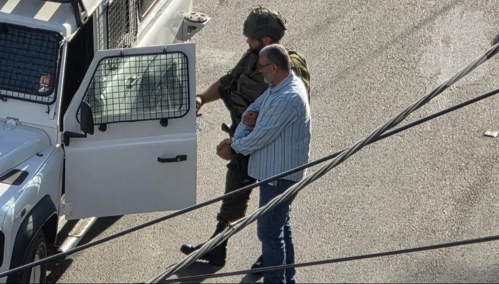 جندي إسرائيلي يقتاد فلسطينياً إلى مركبة عسكرية خلال العملية العسكرية في مخيم قلنديا شمال القدس. (النهار)