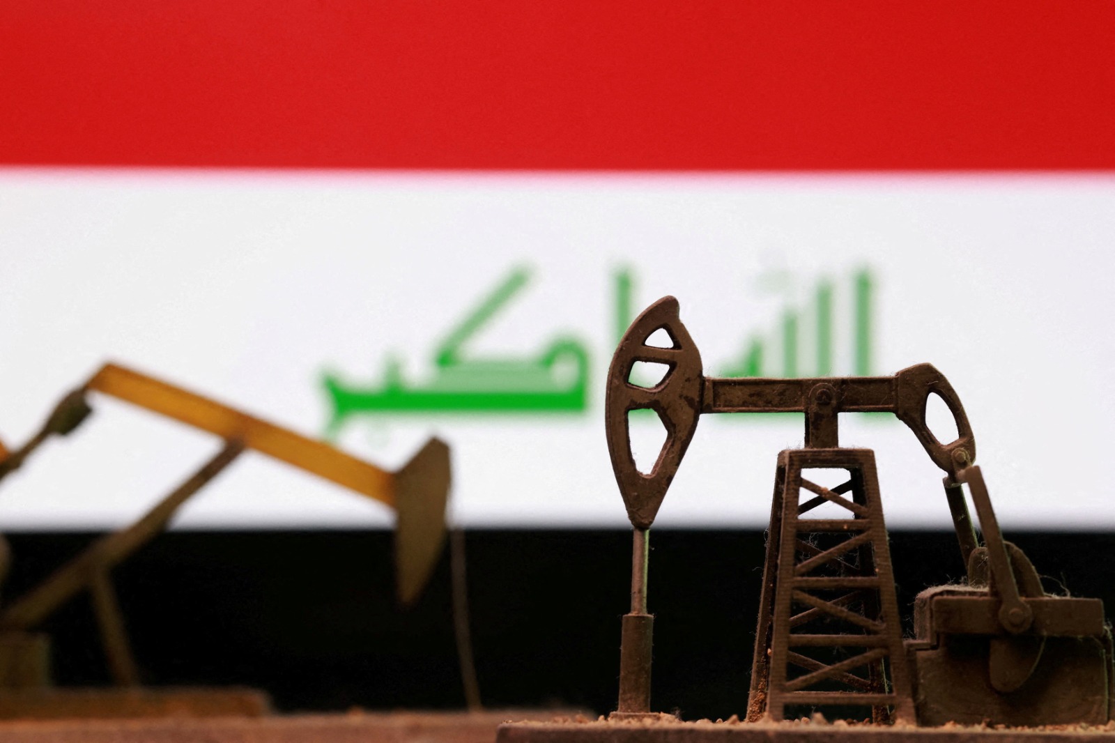 صورة توضيحية لمنصات حفر نفط خلفها علم العراق (رويترز)