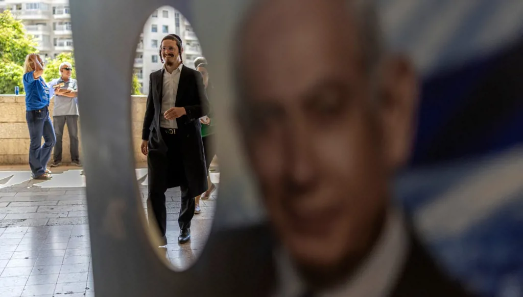 أحد أعضاء "الليكود" أمام صورة لرئيس الوزراء الإسرائيلي بنيامين نتنياهو خلال الانتخابات التمهيدية للحزب في 17 آب/أغسطس 2026. (أ ف ب)