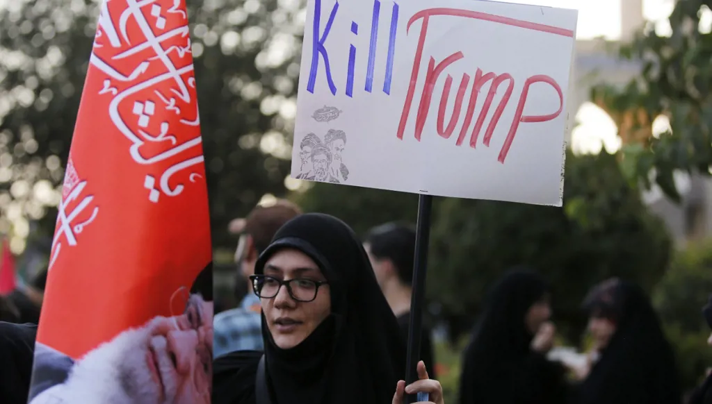 مشاركة إيرانية تحمل لافتة كُتب عليها "اقتلوا ترامب"، إلى جانب صورة للمرشد الإيراني الراحل علي خامنئي، خلال تجمع في إيران. (رويترز)