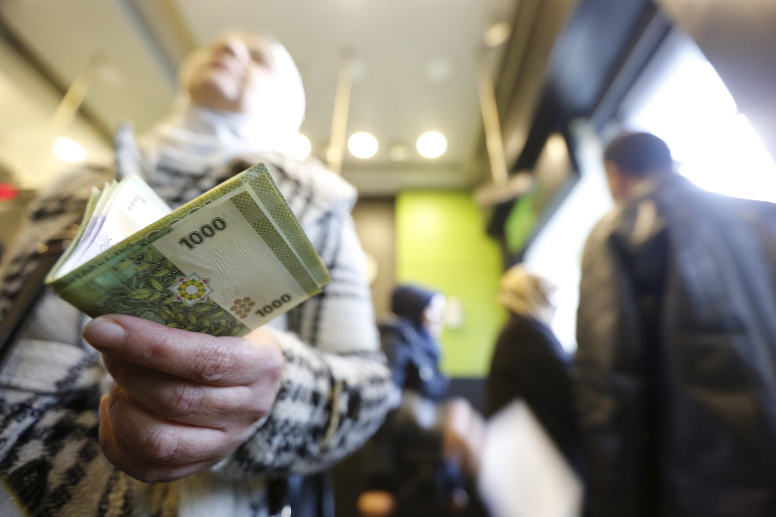 امرأة تحمل نقودا ورقية من الليرة السورية. ويعتمد السوريون على النقد في كل تعاملاتهم ( رويترز)