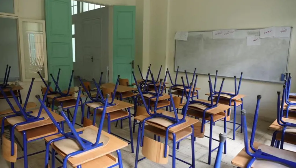 مقاعد فوق طاولات أحد الصفوف في مدرسة رسمية مغلقة في بيروت (رويترز). 