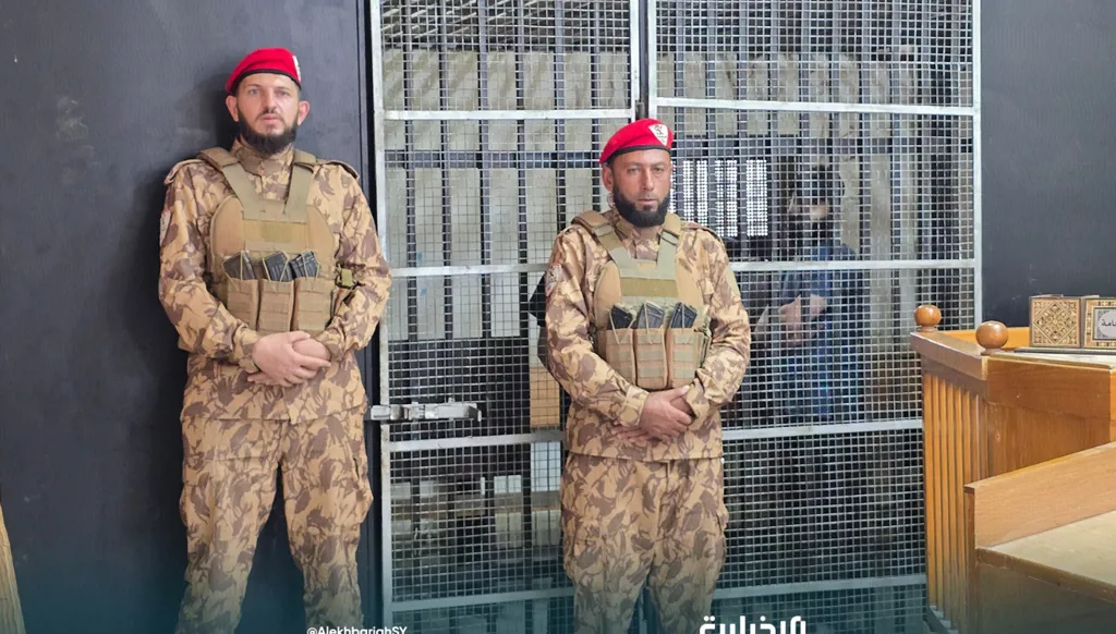 متّهم خلف القضبان خلال جلسة النطق بالحكم بحق متهمين بارتكاب انتهاكات في أحداث الساحل السوري في حلب. (الإخبارية السورية)