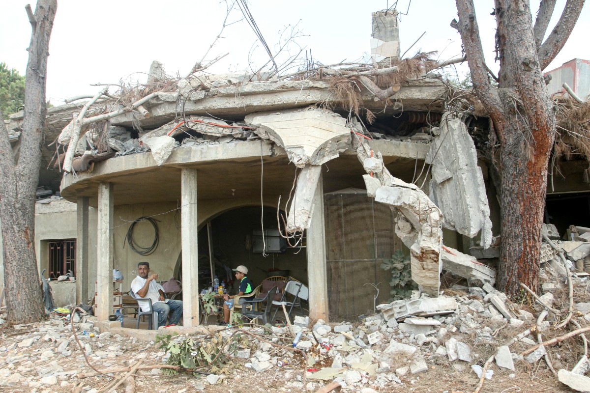 يجلس السكان عند مدخل منزلهم الذي دمره الجيش الإسرائيلي في بلدة زوطر الغربية جنوب لبنان في 8 أغسطس 2026 (أ ف ب)