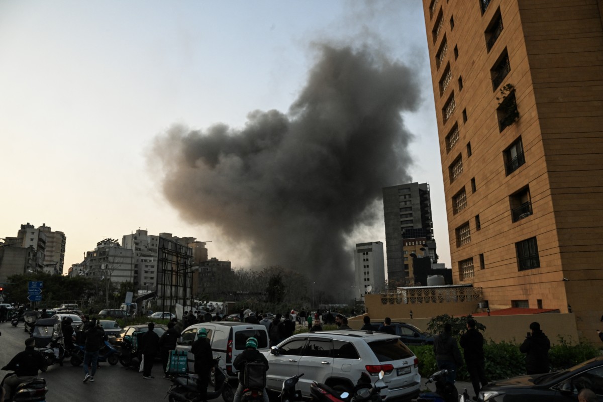 يشاهد الناس عمودًا من الدخان يتصاعد عقب ضربة صاروخية إسرائيلية في حي الباشورة بوسط بيروت في 12 آذار/مارس 2026 (أ ف ب)