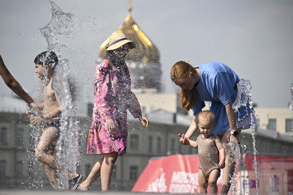 يواجهون الحر بالماء في أحد متنزهات موسكو (وكالات)