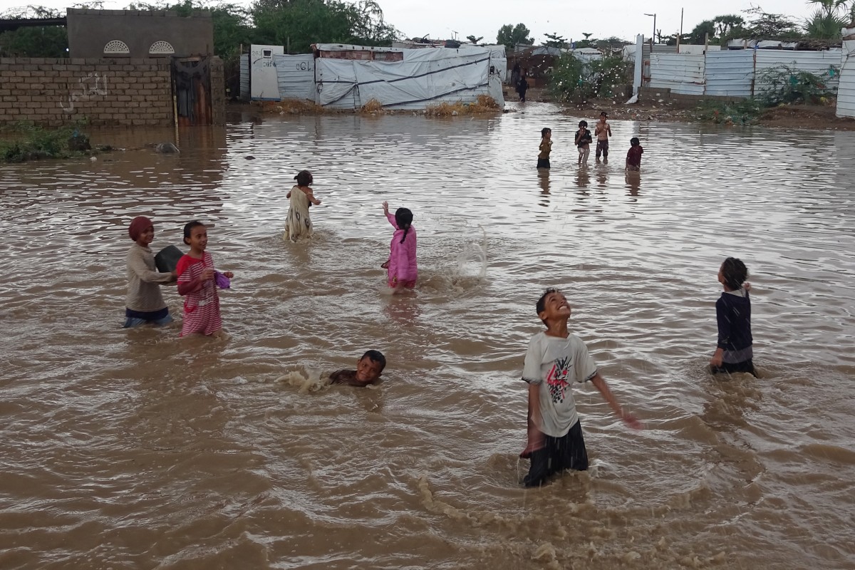 أطفال يمنيون نازحون يلعبون في مياه تجمّعت بعد تساقط غزير للأمطار (أف ب)