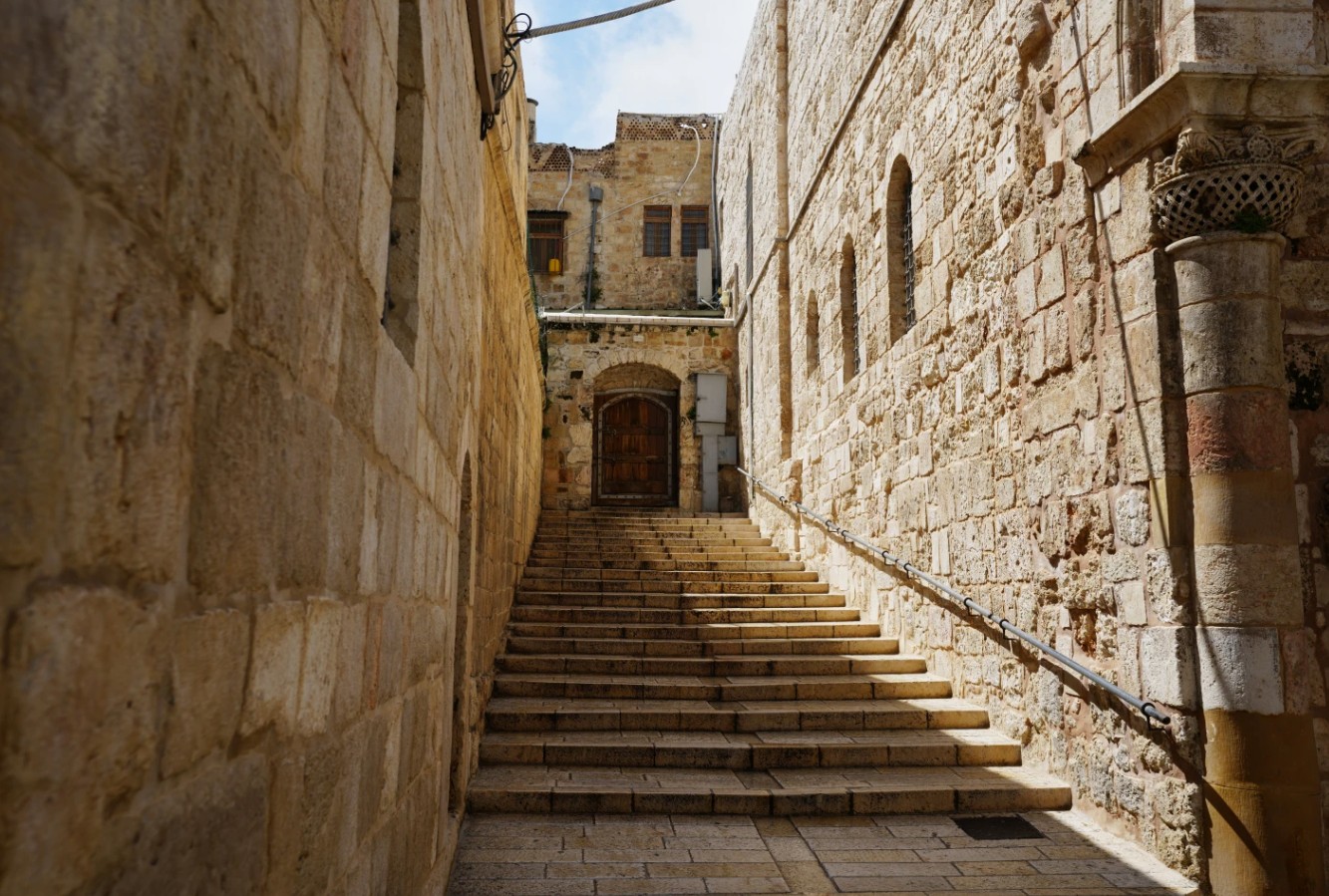 باب كنيسة كنيسة القيامة في القدس القديمة يقف مغلقًا، وسلالمها الخالية تؤدي إلى مدخل المكان المقدس، بعد أن أُغلق الباب أمام الزوار في 27 آذار/مارس 2026 بسبب التوترات والأوضاع الأمنية المتعلقة بالحرب بين الولايات المتحدة وإسرائيل وإيران. (الصورة أ ب)