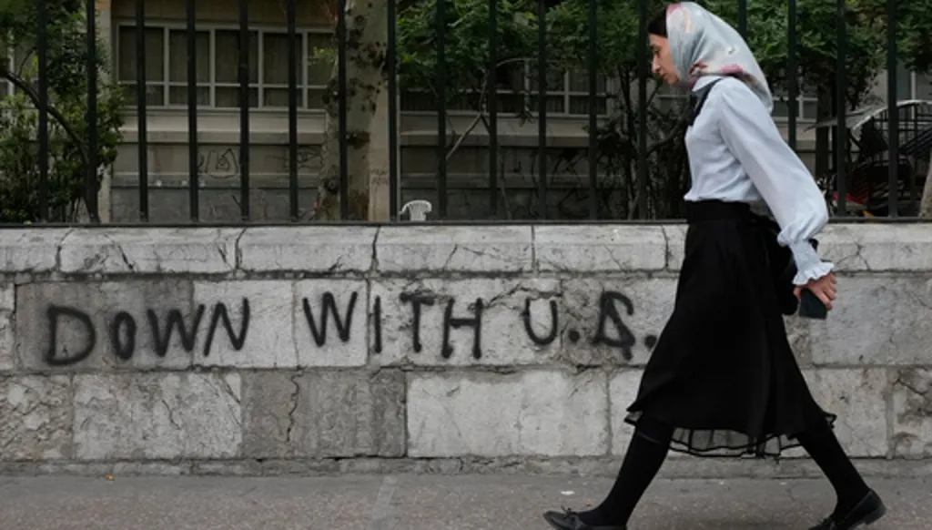 A woman walks past an anti-U.S. graffiti painted on the wall of the Tehran University on Enqelab-e-Eslami (Islamic Revolution) street in downtown Tehran, Iran, Saturday, April 25, 2026. (AP Photo/Vahid Salemi)
