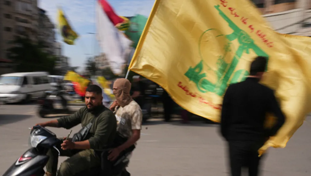 Men ride a scooter while waving a Hezbollah flag during a small gathering in Dahiyeh, Beirut's southern suburbs, Lebanon, Saturday, April 25, 2026. (AP Photo/Hassan Ammar)