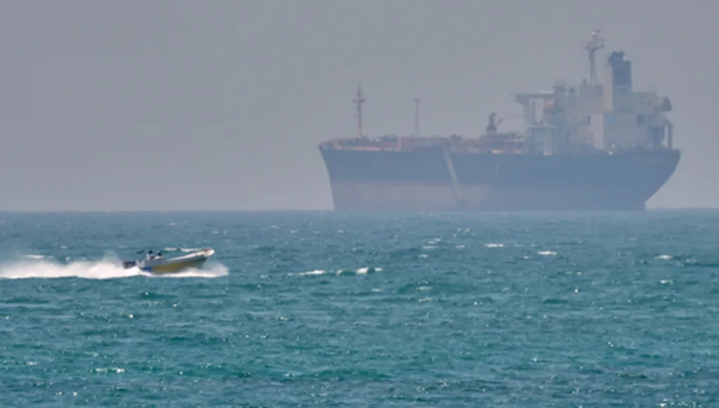 FILE - A boat sails past a tanker anchored on the Strait of Hormuz off the coast Qeshm island, Iran, April 18, 2026. (AP Photo/Asghar Besharati, File)