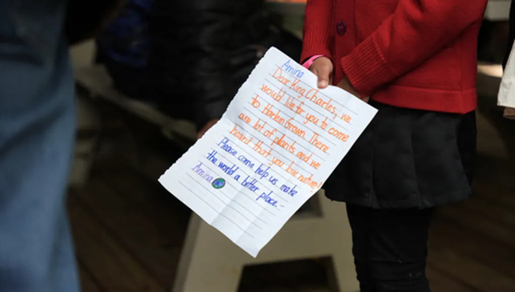 Britain's King Charles III receives a letter from a young attendee at a Harlem Grown event, Wednesday, April 29, 2026, in New York. (AP Photo/Angelina Katsanis, Pool)