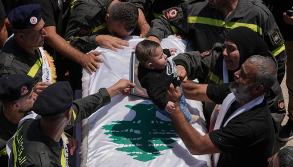 A man, right, puts the five months son of Lebanese Civil Defense worker Hussein Ali Satti on his father's coffin who was killed alongside two colleagues in an Israeli strike on Tuesday, during his funeral procession in the southern port city of Tyre, Lebanon, Thursday, April 30, 2026. (AP Photo/Hussein Malla)