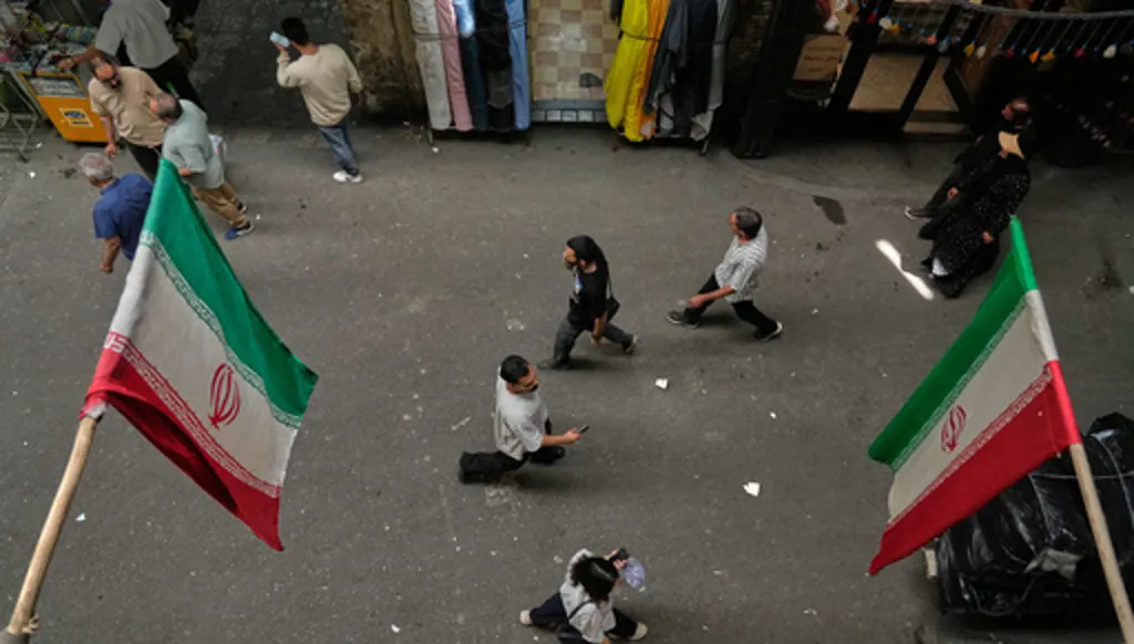 People walk as Iranian flags hang in the Grand Bazaar in Tehran, Sunday, May 3, 2026. (AP Photo/Vahid Salemi)