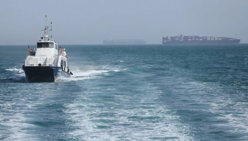 A patrol boat moves through the water as cargo ships sit at anchor in the Strait of Hormuz off Bandar Abbas, Iran, Saturday, May 2, 2026.(Amirhosein Khorgooi/ISNA via AP)