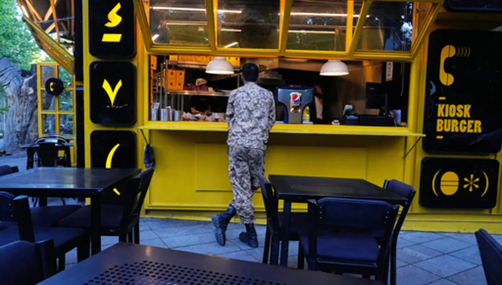 A Revolutionary Guard soldier stands at the counter of a fast food restaurant in northern Tehran, Iran, Sunday, May 10, 2026. (AP Photo/Vahid Salemi)