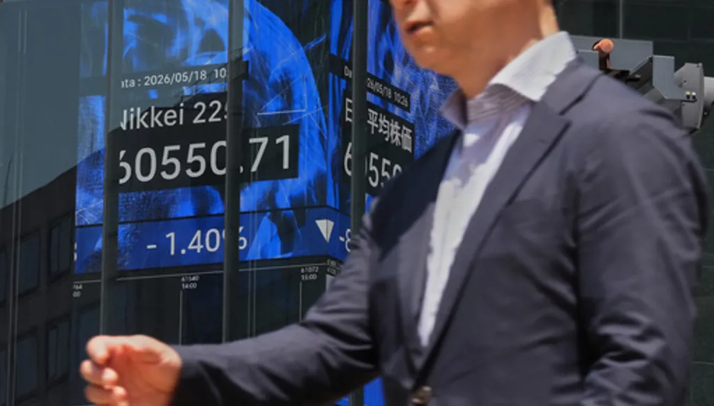 A person walks in front of an electronic board at a business building showing Japan's Nikkei index, Monday, May 18, 2026, in Tokyo. (AP Photo/Eugene Hoshiko)