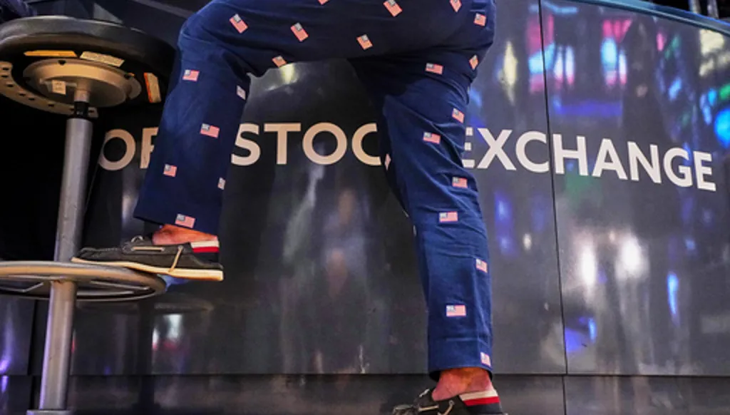 Specialist Michael Pistillo wears pants adorned with American flags as he works on the floor of the New York Stock Exchange, Friday, May 22, 2026. (AP Photo/Richard Drew)