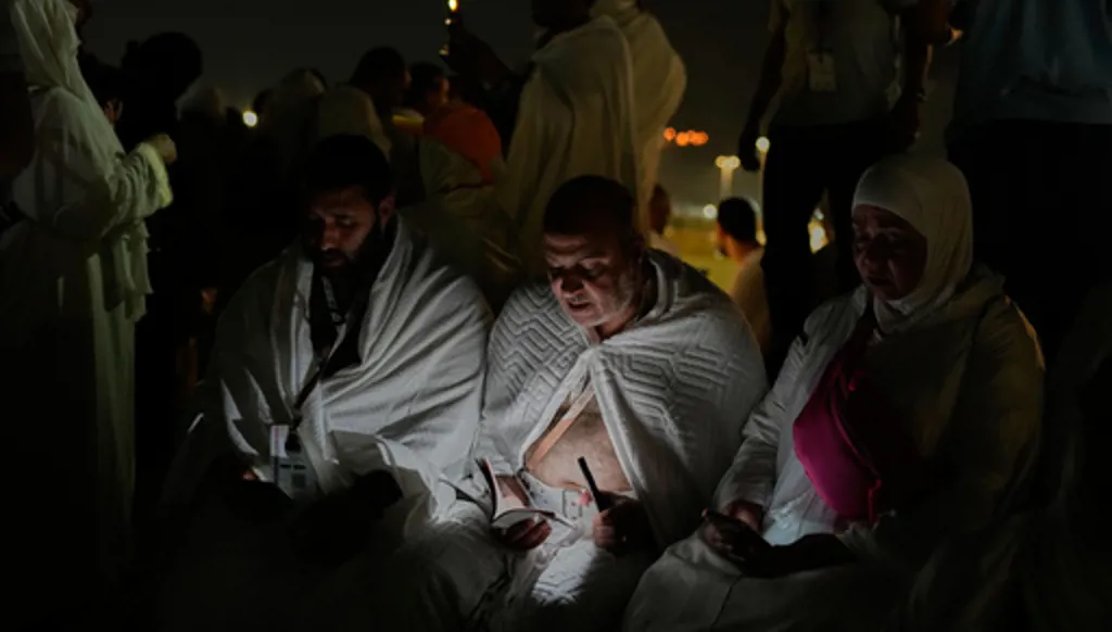 Muslim pilgrims read a copy of Islam's holy book Quran atop of the rocky hill known as the Mountain of Mercy, on the Plain of Arafat, during the annual Hajj pilgrimage near the holy city of Mecca, Saudi Arabia, Tuesday, May 26, 2026. (AP Photo/Altaf Qadri)