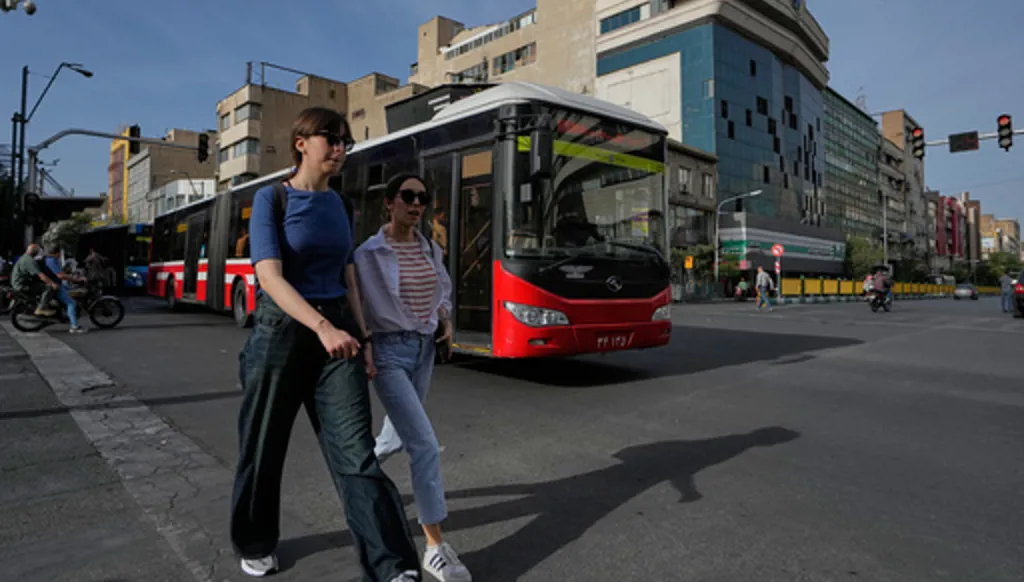 Women walk as a public bus drive in an intersection in downtown Tehran, Iran, Thursday, May 28, 2026. (AP Photo/Vahid Salemi)