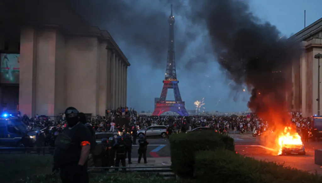 A car burns and fireworks explode as police watch PSG supporters celebrate in Paris, Saturday, May 30, 2026 after the Champions League final soccer match between Paris Saint-Germain and Arsenal that's being played in Budapest., PSG won the game. (AP Photo/Thomas Padilla)