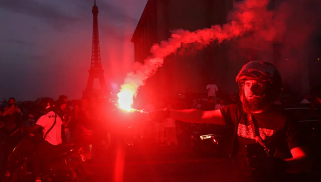 A man holds a flare as PSG supporters celebrate in Paris, Saturday, May 30, 2026 after the Champions League final soccer match between Paris Saint-Germain and Arsenal that's being played in Budapest., PSG won the game. (AP Photo/Thomas Padilla)