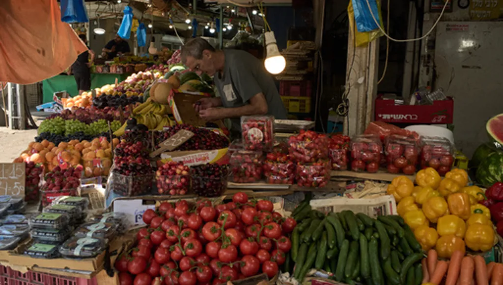 A vendor checks the fruits on his stand at a local street market following air raid sirens warning of incoming Iranian missiles in Haifa, northern Israel, Monday, June 8, 2026. (AP Photo/Leo Correa)
