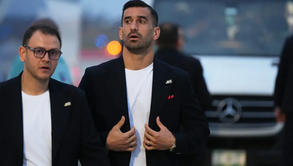 Iran's Ehsan Hajisafi, center, walks with a team official as he arrives with his teammates for the World Cup soccer tournament in Tijuana, Mexico, Sunday, June 7, 2026. (AP Photo/Gregory Bull)