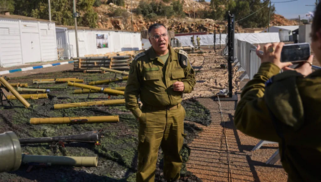 Avichay Adraee, the Israeli military’s Arabic language spokesman, stands beside weapons the army says were seized from Hezbollah in Lebanon, at an army base in northern Israel, Dec. 23, 2024. (AP Photo/Ohad Zwigenberg)