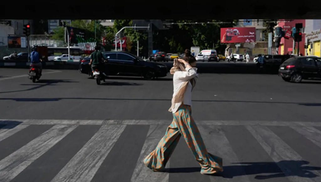 A woman adjusts her headscarf as she crosses an intersection in northern Tehran, Wednesday, June 10, 2026. (AP Photo/Vahid Salemi)