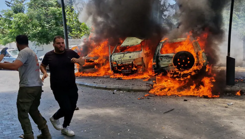 A man runs past burning cars following an Israeli airstrike in the southern port city of Sidon, Lebanon, Wednesday, June 10, 2026. (AP Photo/Mohammed Zaatari)