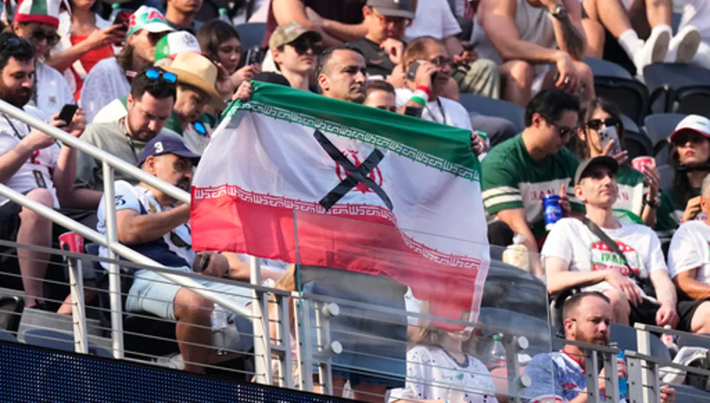 An attendees holds an Iranian flag with an "X" on it before the World Cup Group G soccer match between Iran and New Zealand in Inglewood, Calif., near Los Angeles, Monday, June 15, 2026. (AP Photo/Mark J. Terrill)
