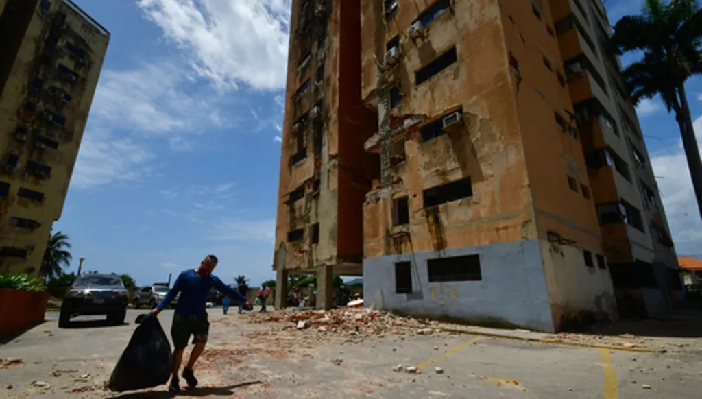A man walks past a building damaged by earthquakes that struck Puerto Cabello, Venezuela, a day earlier, Thursday, June 25, 2026. (AP Photo/Jacinto Oliveros)