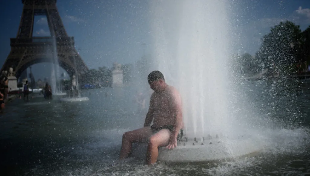 A person cools off at Trocadero fountain near the Eiffel Tower during a heat wave in Paris, Wednesday, June 24, 2026. (AP Photo/Christophe Ena)