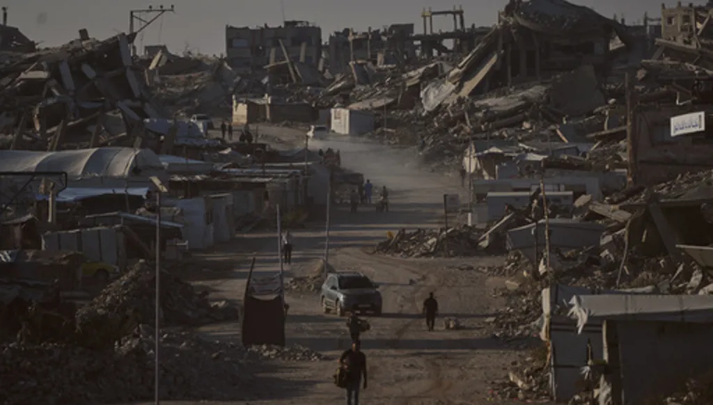 Palestinians walk along a road surrounded by buildings destroyed in Israeli military strikes during the Israel-Hamas war, in Jabaliya, Gaza Strip, Thursday, July 2, 2026. (AP Photo/Jehad Alshrafi)